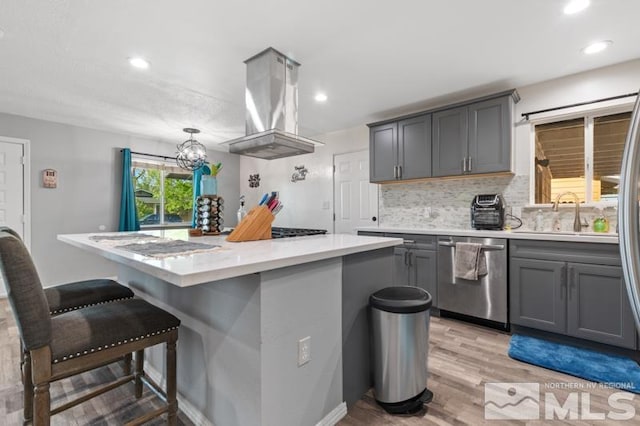 kitchen featuring gray cabinets, light hardwood / wood-style floors, island range hood, and dishwasher