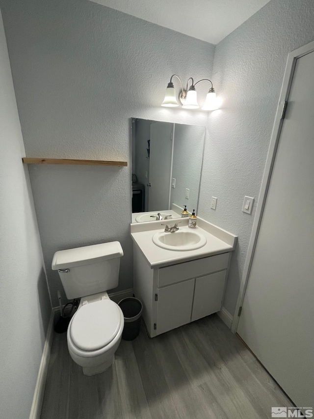 bathroom with wood-type flooring, vanity, and toilet