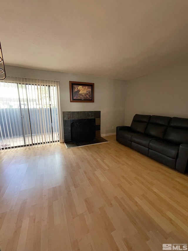 living room featuring a tile fireplace and light wood-type flooring