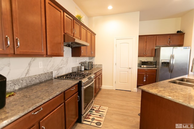 kitchen with light stone counters, sink, tasteful backsplash, stainless steel appliances, and light wood-type flooring