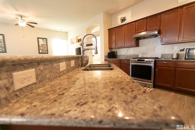 kitchen featuring stainless steel range oven, tasteful backsplash, sink, light hardwood / wood-style flooring, and extractor fan