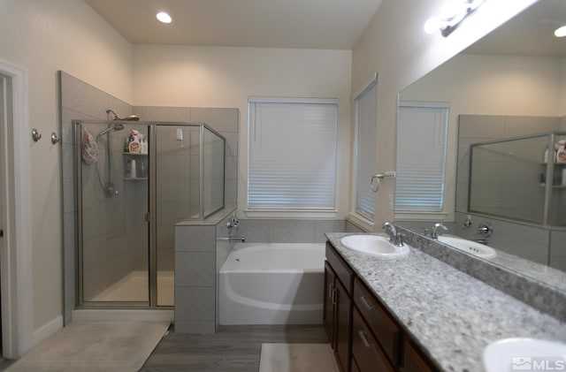 bathroom with wood-type flooring, vanity, and plus walk in shower