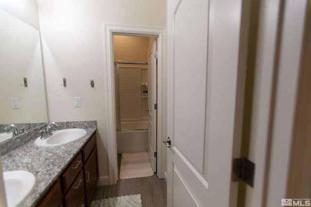 bathroom featuring vanity, hardwood / wood-style floors, and combined bath / shower with glass door