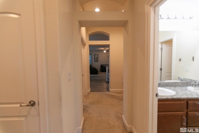 hall featuring light carpet and sink