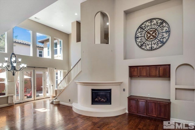 living room with a wealth of natural light, an inviting chandelier, and dark hardwood / wood-style flooring