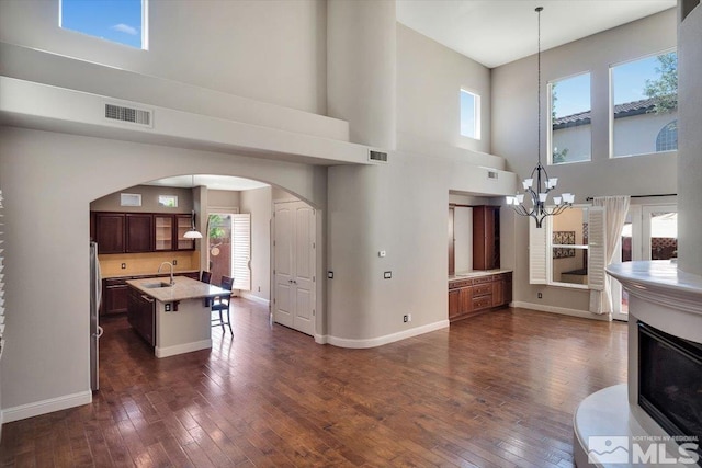 living room featuring dark hardwood / wood-style floors, plenty of natural light, a towering ceiling, and sink