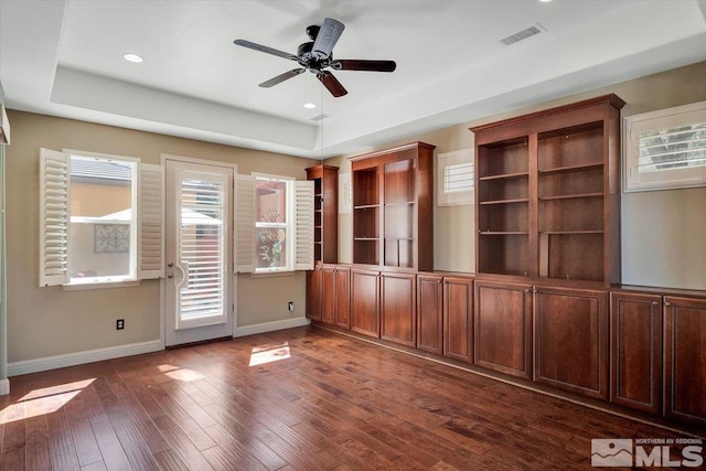 unfurnished room with dark wood-type flooring, ceiling fan, and a raised ceiling