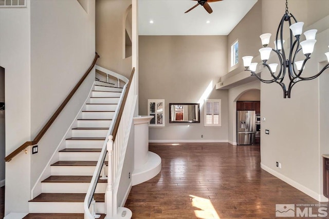 interior space featuring a high ceiling, dark hardwood / wood-style floors, and ceiling fan with notable chandelier