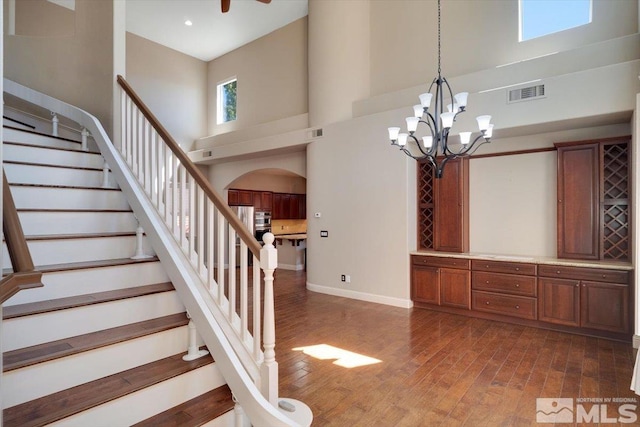 interior space with an inviting chandelier, a towering ceiling, and dark hardwood / wood-style floors