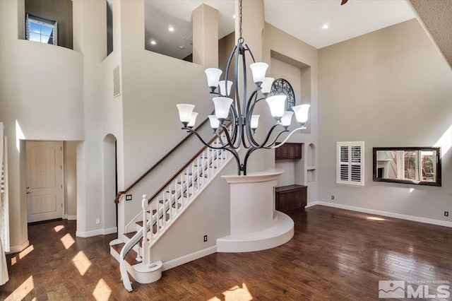 stairs featuring a towering ceiling, dark hardwood / wood-style floors, and an inviting chandelier