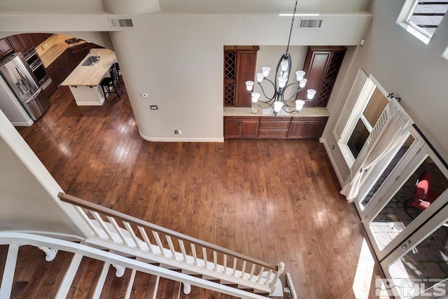 entryway with a towering ceiling, a wealth of natural light, an inviting chandelier, and dark hardwood / wood-style flooring