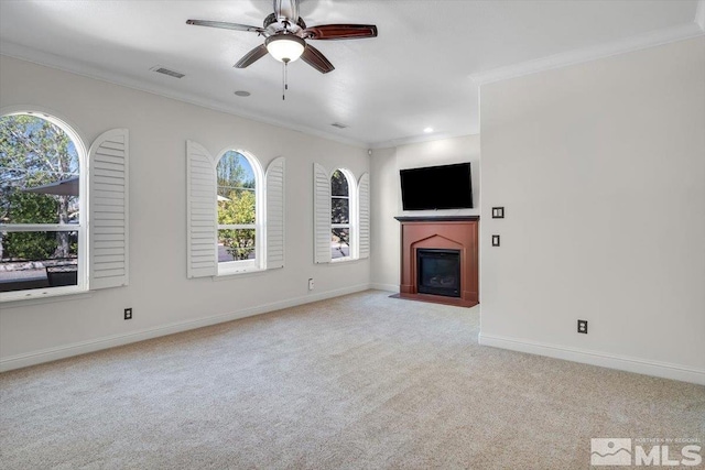 unfurnished living room featuring ceiling fan, carpet floors, and ornamental molding