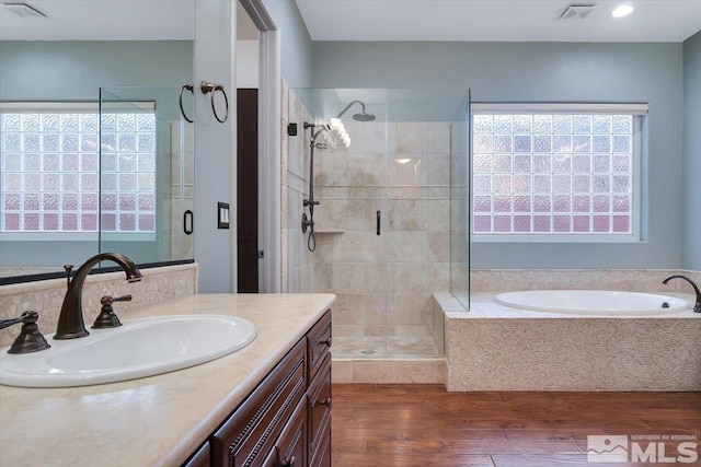 bathroom with wood-type flooring, independent shower and bath, and oversized vanity