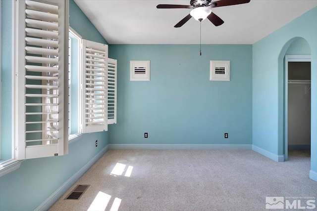 unfurnished bedroom featuring carpet flooring, ceiling fan, and multiple windows