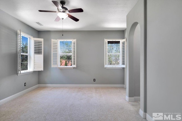 spare room featuring ceiling fan, a textured ceiling, and light carpet