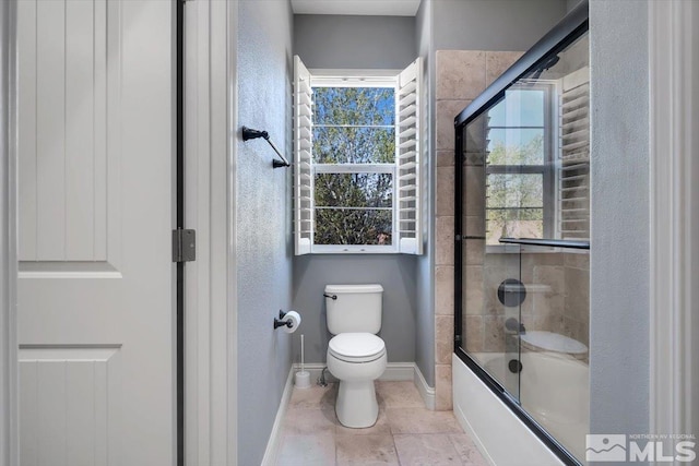 bathroom featuring tile floors, combined bath / shower with glass door, and toilet