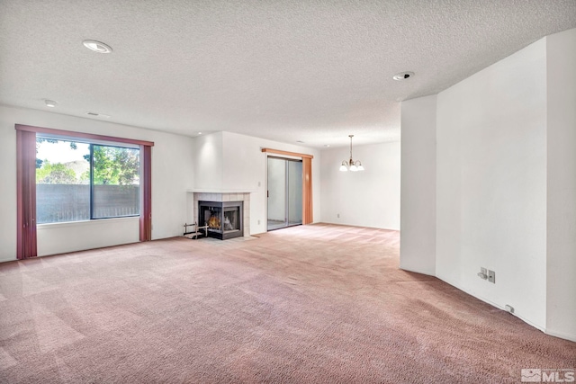 unfurnished living room with light carpet, a textured ceiling, a fireplace, and a notable chandelier