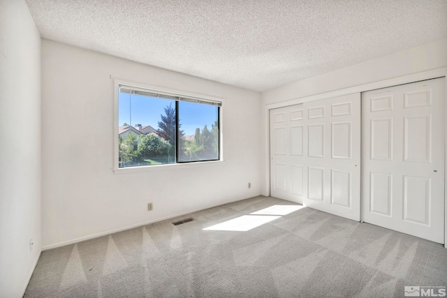 unfurnished bedroom featuring a closet, light colored carpet, and a textured ceiling