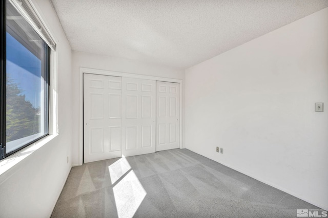 unfurnished bedroom with a closet, light colored carpet, and a textured ceiling