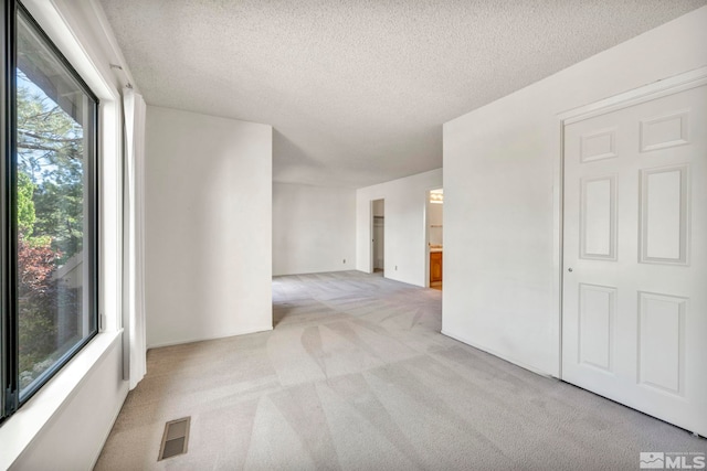 empty room with a textured ceiling and light carpet