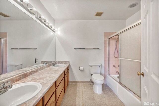 full bathroom featuring vanity, combined bath / shower with glass door, and toilet