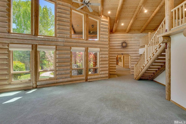 unfurnished living room with high vaulted ceiling, log walls, and carpet flooring