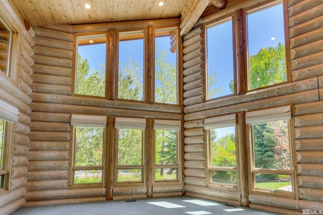 interior space featuring carpet flooring, wooden ceiling, a high ceiling, and log walls