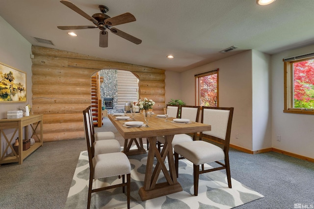 dining space featuring ceiling fan, a healthy amount of sunlight, log walls, and carpet flooring