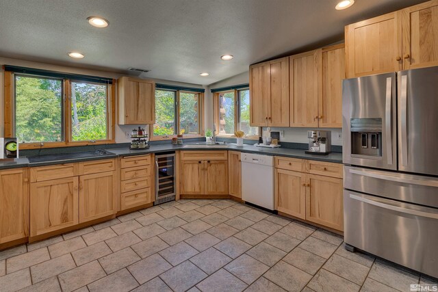 kitchen featuring wine cooler, stainless steel fridge, dishwasher, light tile floors, and lofted ceiling