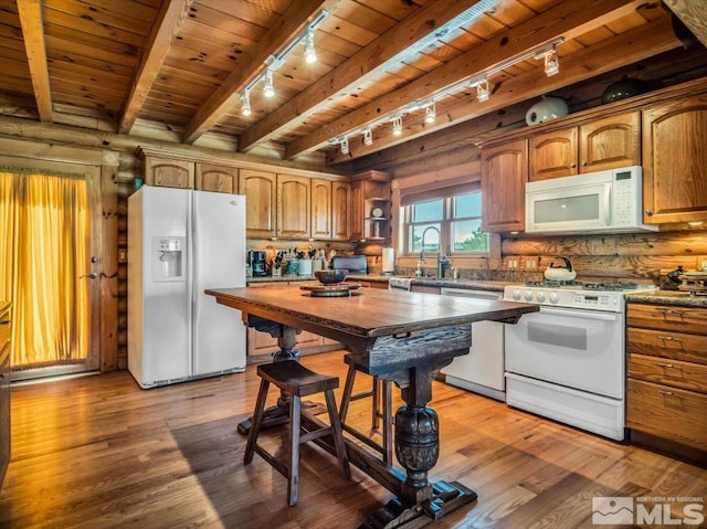 kitchen featuring beam ceiling, rustic walls, white appliances, and wood ceiling