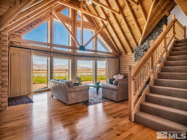 unfurnished living room with log walls, wooden ceiling, high vaulted ceiling, wood-type flooring, and beamed ceiling