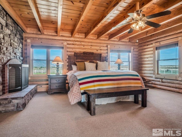 carpeted bedroom featuring ceiling fan, beam ceiling, a fireplace, wood ceiling, and rustic walls