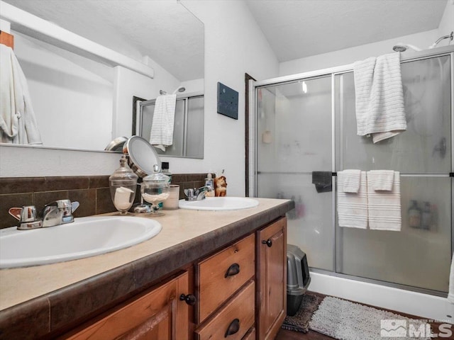 bathroom with a shower with shower door, large vanity, and double sink