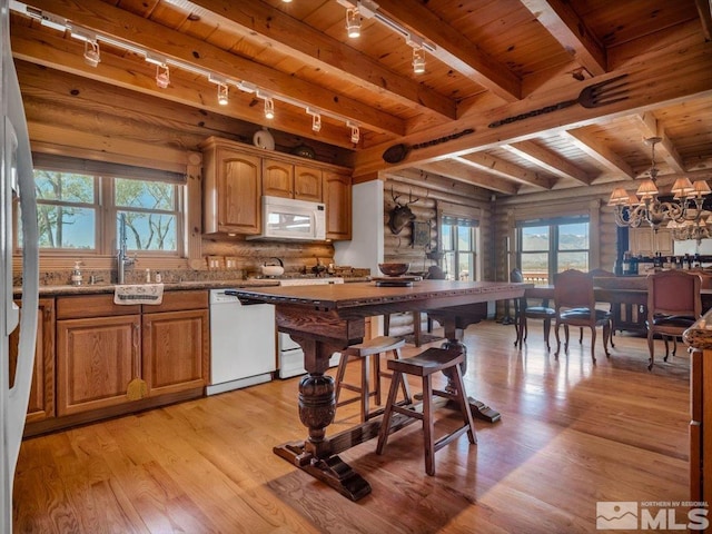 kitchen featuring hanging light fixtures, wooden ceiling, beam ceiling, rustic walls, and white appliances