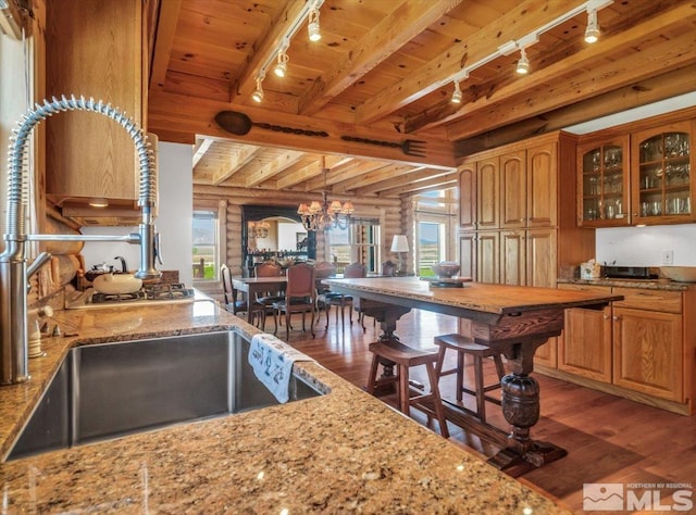 kitchen with hardwood / wood-style floors, beam ceiling, wood ceiling, track lighting, and rustic walls