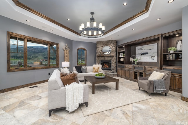 living room featuring built in features, a stone fireplace, a mountain view, and a raised ceiling