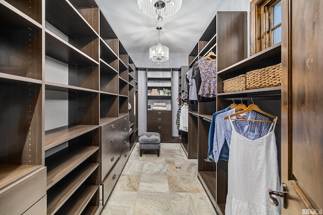 spacious closet featuring light tile flooring and an inviting chandelier