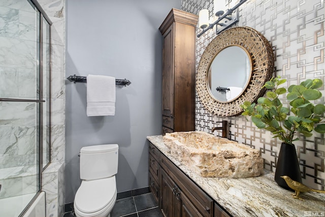 full bathroom featuring tile flooring, vanity, toilet, and bath / shower combo with glass door