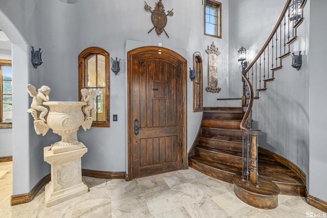 entryway with tile floors, plenty of natural light, and a towering ceiling