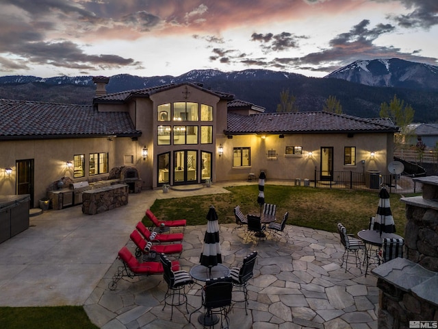 back house at dusk featuring a mountain view, a fire pit, and a patio