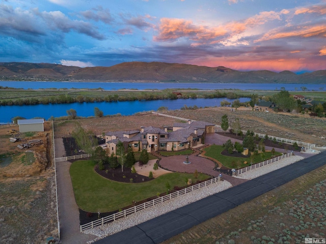 aerial view at dusk featuring a water and mountain view