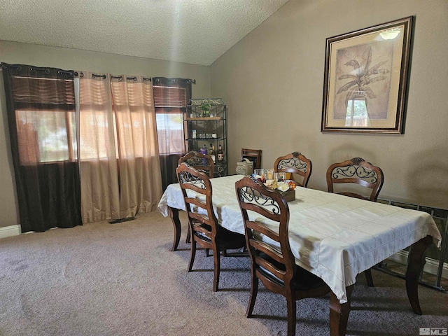 carpeted dining room with lofted ceiling and a textured ceiling