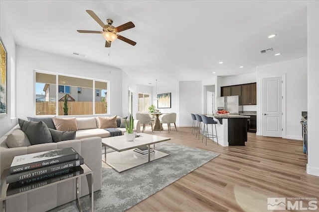 living room with a healthy amount of sunlight, ceiling fan, and light hardwood / wood-style flooring