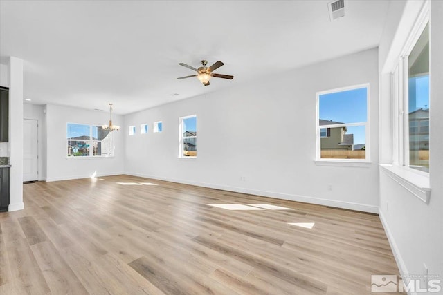 unfurnished living room with ceiling fan with notable chandelier and light hardwood / wood-style flooring