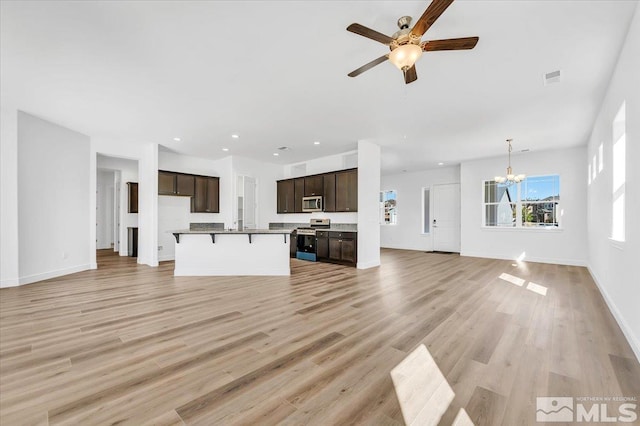 unfurnished living room featuring ceiling fan with notable chandelier and light hardwood / wood-style flooring