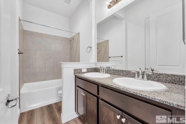 full bathroom with hardwood / wood-style flooring, vanity, toilet, and tiled shower / bath combo