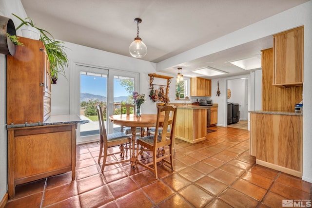 tiled dining area with a tray ceiling and washer / dryer