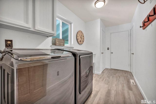 clothes washing area with cabinets, light hardwood / wood-style floors, and separate washer and dryer