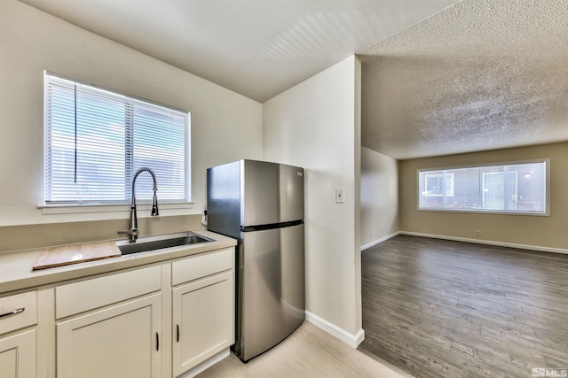 kitchen featuring a healthy amount of sunlight, light hardwood / wood-style floors, a textured ceiling, and stainless steel fridge