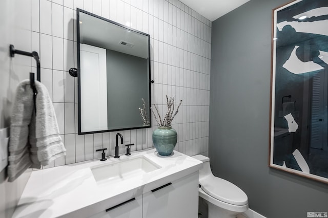 bathroom featuring oversized vanity, toilet, and tile walls